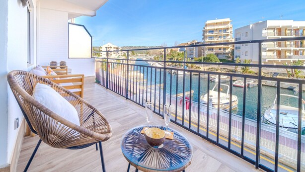 A balcony with wicker chairs and a glass table, overlooking a marina with boats and buildings. - Venecia Beach Apartment Javea Arenal (Javea / Xàbia)
