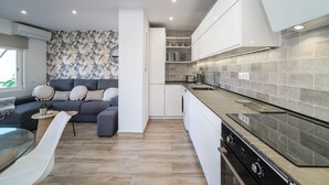 A modern kitchen with white cabinets, a built-in oven, and a grey tiled backsplash. - Venecia Beach Apartment Javea Arenal (Javea / Xàbia)