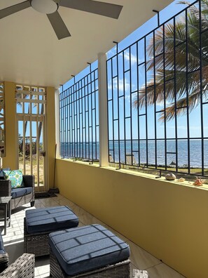Ein Balkon mit Korbmöbeln, Blick auf das Meer und einem Metallgeländer.