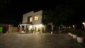 A modern two-story house with a covered patio area, potted plants, and a staircase leading to the upper floor. - Wild Vista Corbett Resort (Dhikuli)
