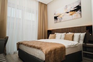 A modern hotel room with a large bed, a desk, and a window with sheer curtains. - Stars Hotel (Jelah)