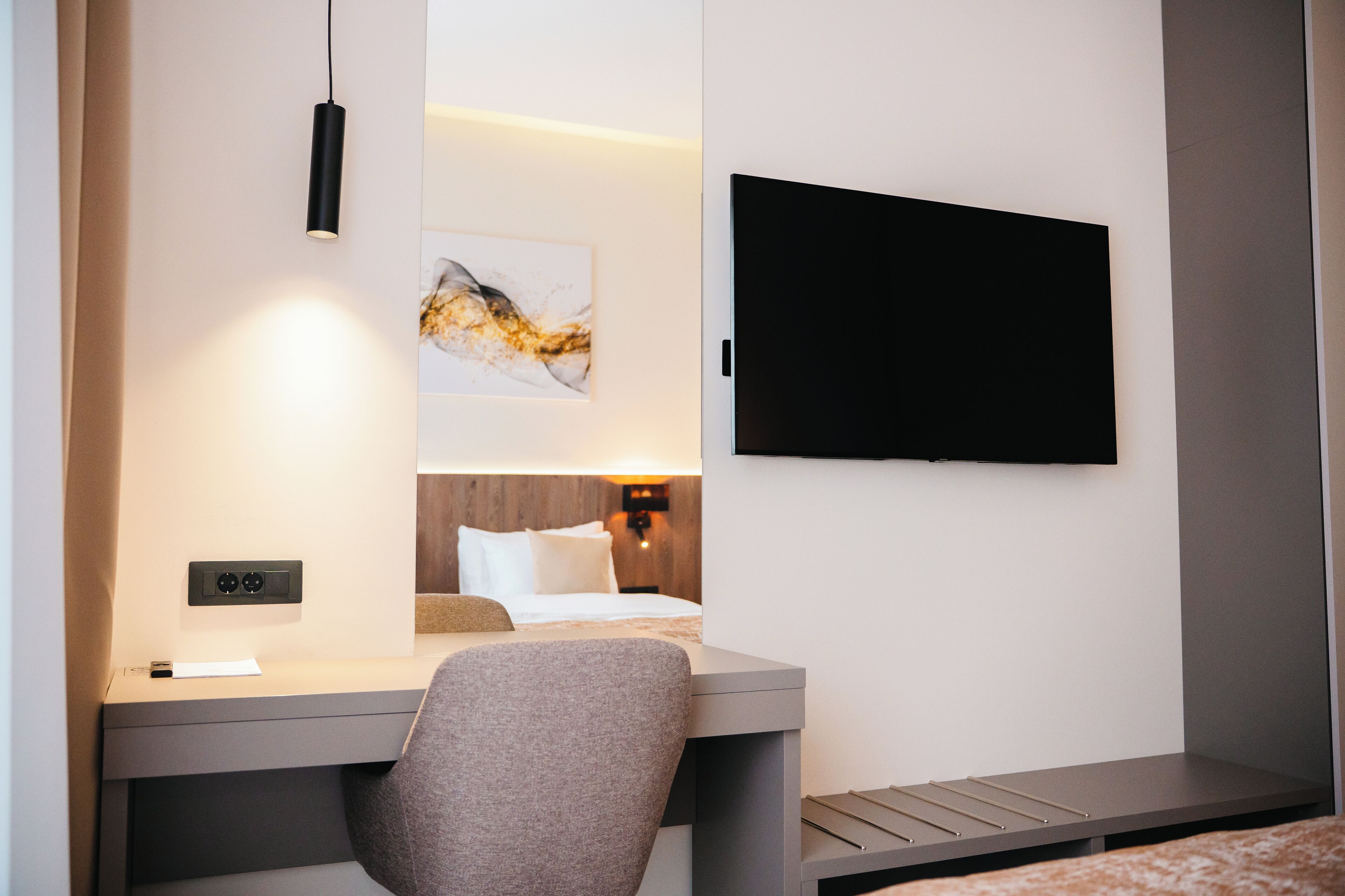 Une chambre d’hôtel équipée d’un lit, d’un bureau, d’une chaise, d’un téléviseur à écran plat et d’une œuvre d’art accrochée au mur.