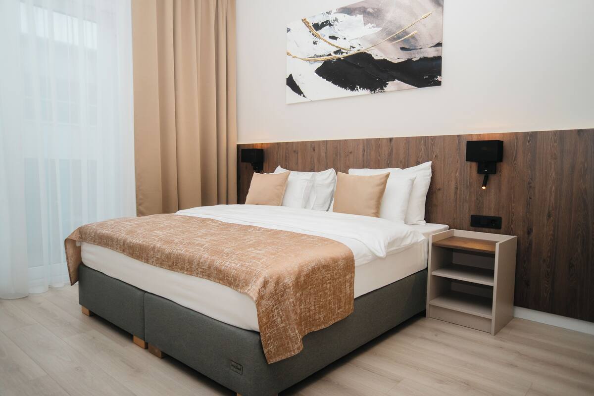 Un dormitorio moderno con una cama grande, cabecera de madera y una mesita de noche.