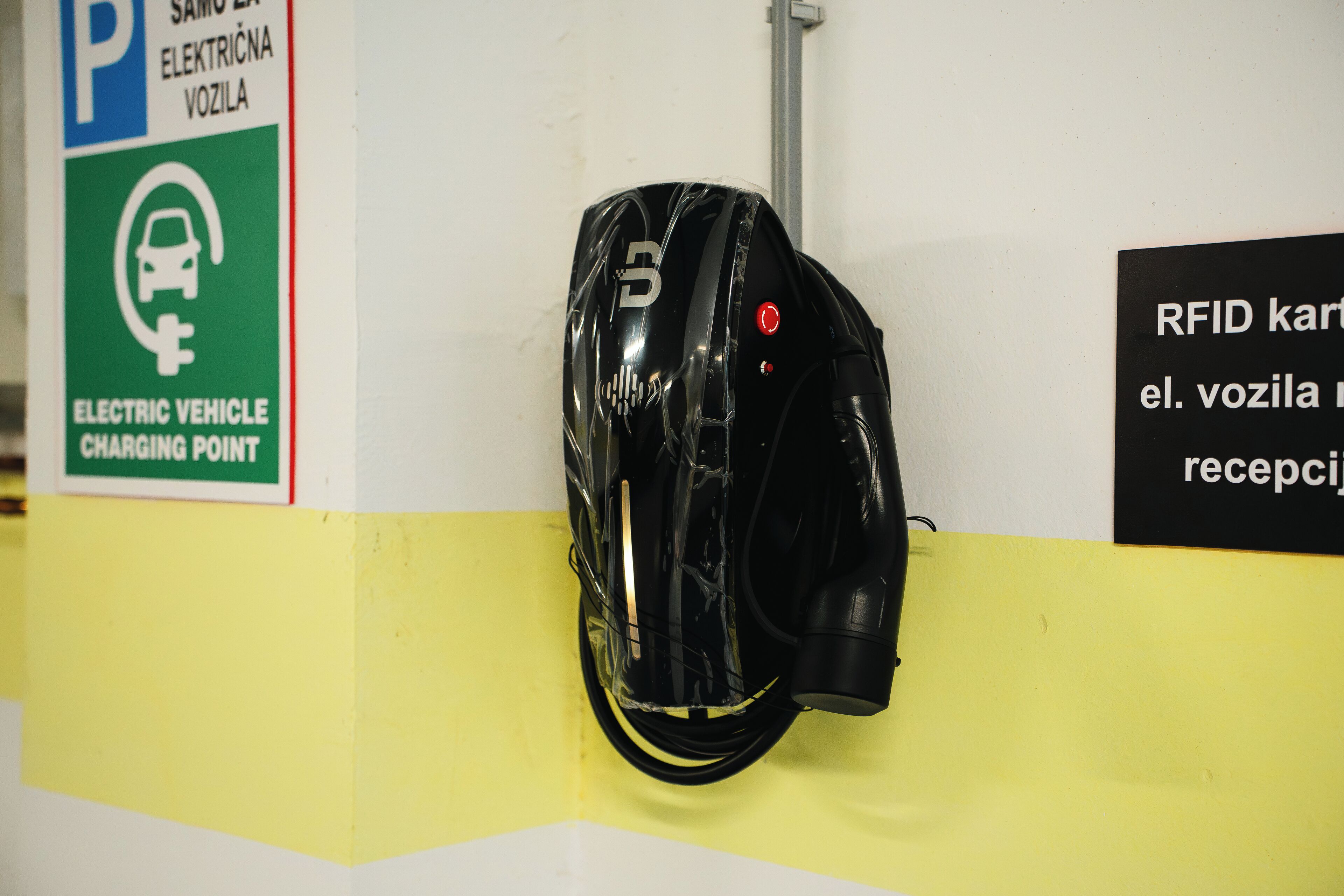 A helmet hanging on a wall with a sign indicating an electric vehicle charging point nearby.