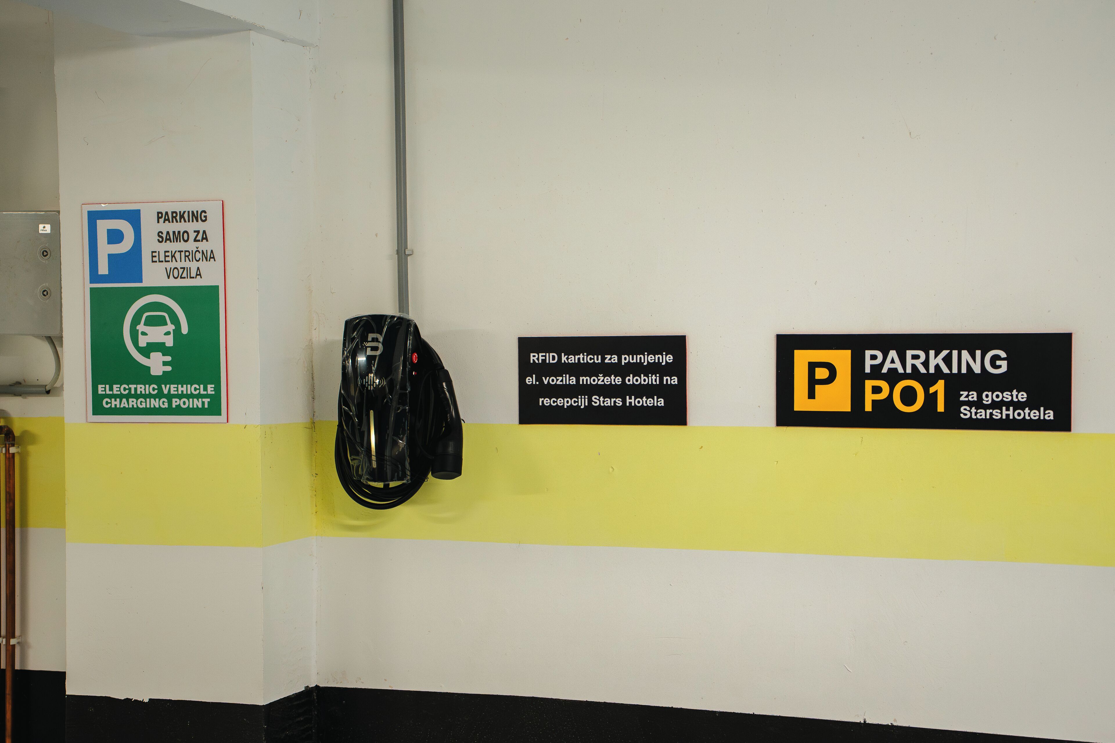 Uma área de estacionamento com sinalização para carregamento de veículos elétricos e estacionamento por cartão RFID no StarsHotel.