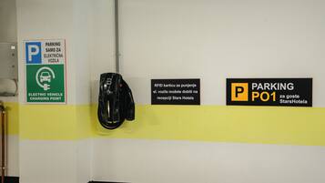 Uma área de estacionamento com sinalização para carregamento de veículos elétricos e estacionamento por cartão RFID no StarsHotel.