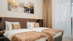 A hotel room with two beds, a wooden headboard, a large abstract painting, and sheer curtains. - Stars Hotel (Jelah)