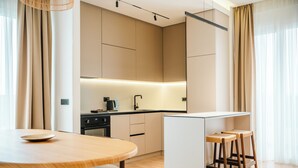 A modern kitchen with a central island, bar stools, and a dining table. - Stars Hotel (Jelah)