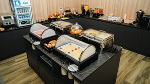 A buffet setup with various food stations, a coffee machine, and a juice dispenser. - Stars Hotel (Jelah)