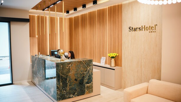 A reception desk with a marble top, wooden paneling on the walls, and a sign reading "StarsHotel". - Stars Hotel (Jelah)