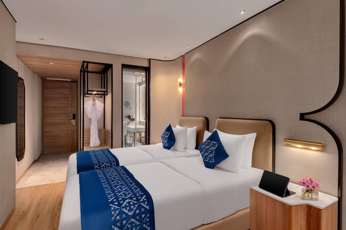 Une chambre d’hôtel avec un lit double, des tables de chevet, un miroir et une vue sur la salle de bain.