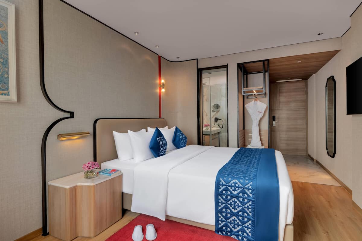 Une chambre d’hôtel avec un lit, une table de chevet et un miroir.