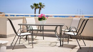 Une table ronde avec quatre chaises, une plante en pot et une vue sur l’océan.