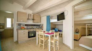 Une cuisine de taille réduite, dotée de meubles de rangement en bois, d’une table à manger et de chaises.