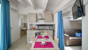 Une cuisine compacte avec un coin repas, un canapé et un téléviseur fixé au mur.