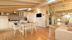 A spacious kitchen with white cabinetry, a dining area with white chairs, and a large window above the kitchen. - Family relaxation in downtown Bergamo (Bergamo)