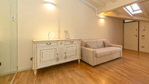 A room with a light-colored wooden floor, a white cabinet with drawers, a beige sofa, and a skylight on the ceiling. - Family relaxation in downtown Bergamo (Bergamo)