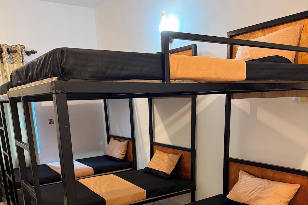 A bunk bed room with three beds, each with a mattress and pillow.