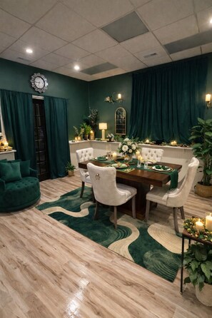 Un comedor con una mesa de madera, sillas blancas tapizadas y un suelo de alfombra verde.