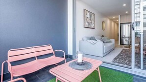 A modern apartment with a pink bench, a white sofa, and a glass door leading to a kitchen.