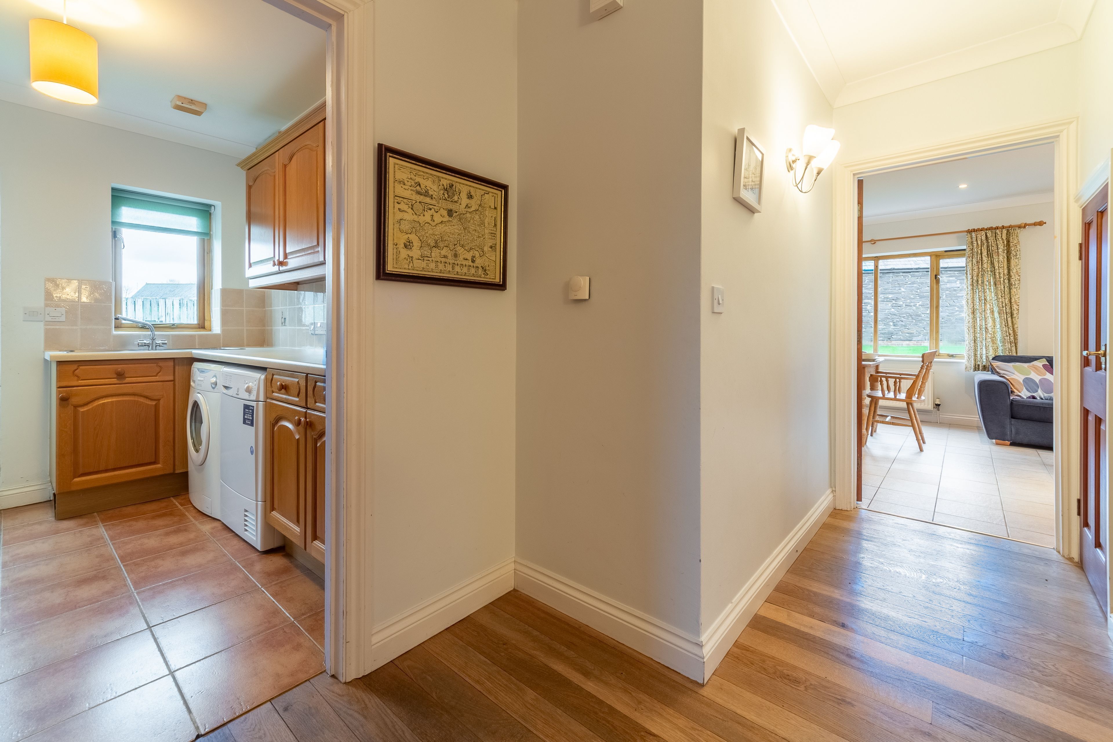 A modern kitchen with wooden cabinets, a washing machine, and a dining area with a table and chairs.