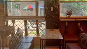A cozy room with a sofa, a small table, and a cushioned bench. There are windows with views of the outside. - Babalao Hotel & Restaurant Malindi (Malindi)