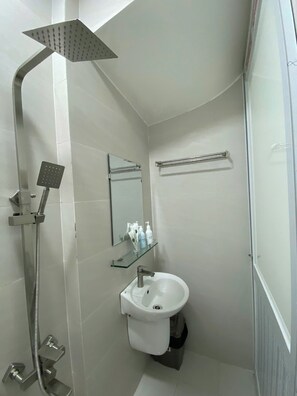 Uma casa de banho moderna com chuveiro, pia e espelho.