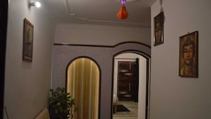 Un pasillo con un arco decorativo, una planta y obras de arte enmarcadas en las paredes.
