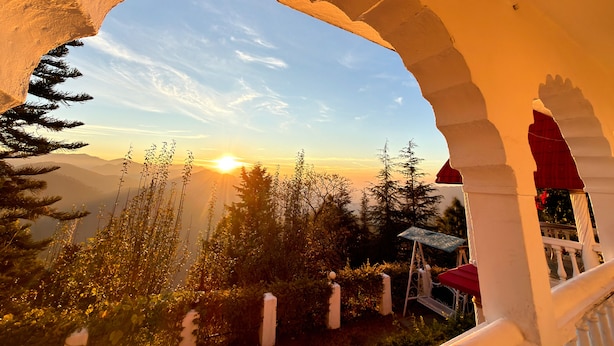 Vista a través de un arco que da a un paisaje montañoso al atardecer.