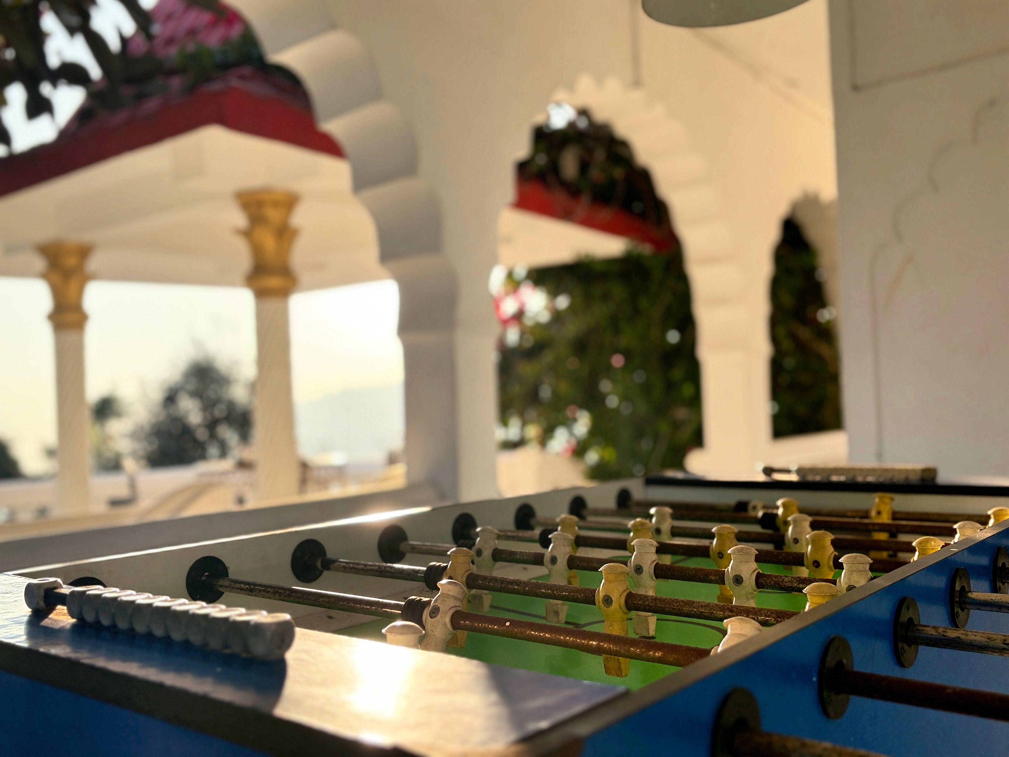 Una mesa de fútbol en una habitación con columnas blancas y vistas al exterior.
