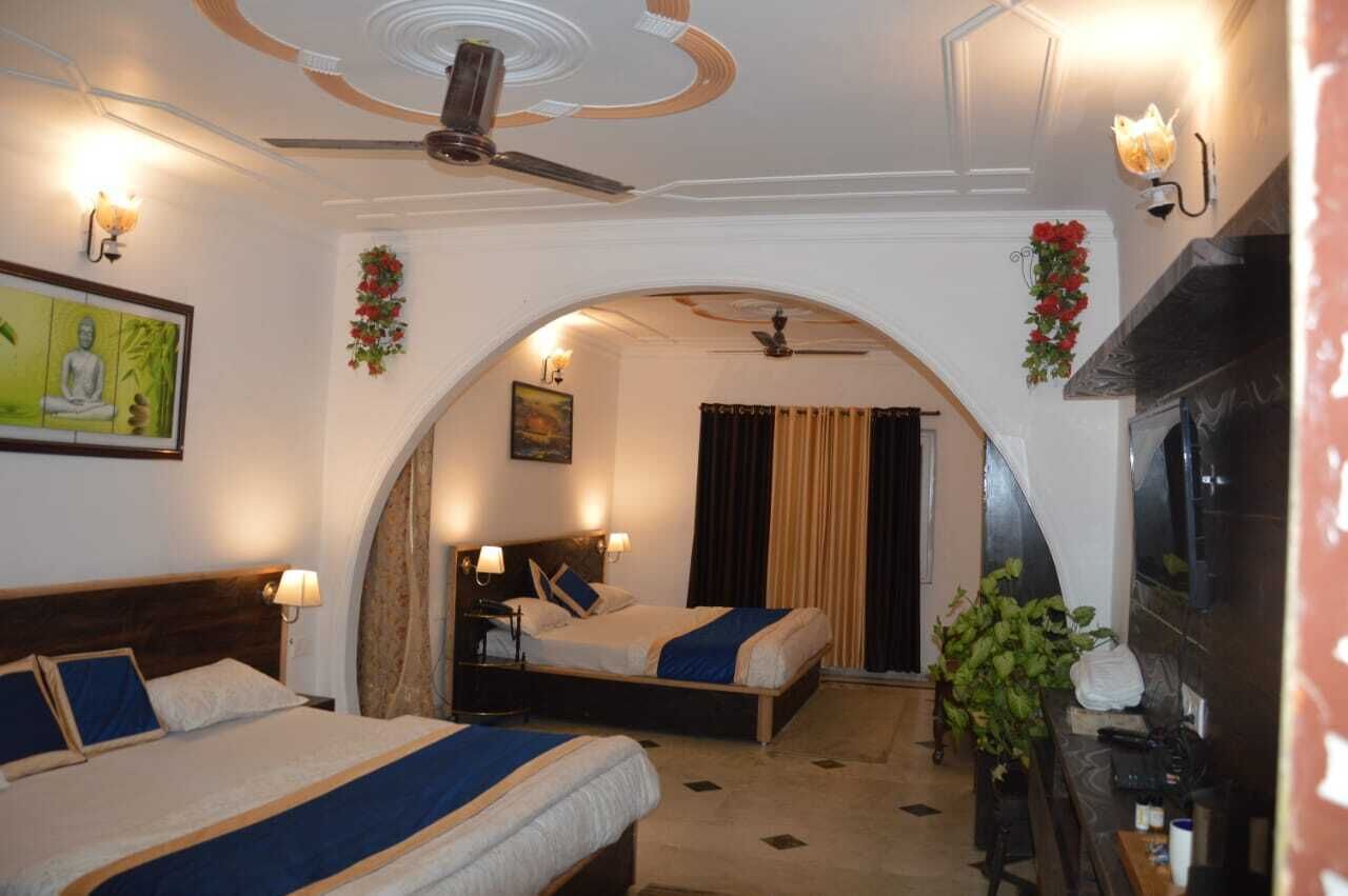 Une chambre d’hôtel avec deux lits, un ventilateur de plafond, une cheminée et un tableau au mur.
