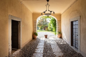 A corridor with a tiled floor, two doors, and a hanging light fixture. - Palazzo Trevignane - La Saletta Verde (San Felice del Benaco)