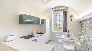 Una cucina moderna con mobili bianchi, forno integrato e una finestra con tende.