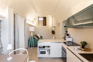A compact kitchen with a dining area, a small living space, and a kitchenette. - Palazzo Trevignane - La Saletta Verde (San Felice del Benaco)