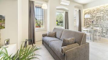 Ein modernes Wohnzimmer mit grauem Sofa, einem Glastisch und einer Steinwand.