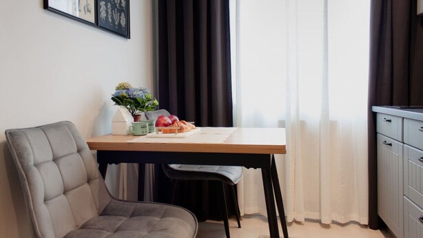 Et moderne værelse med et spisebord, en polstret stol, en lille potteplante og et skab.