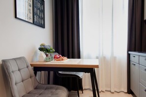 Una habitación moderna con una mesa de comedor, una silla acolchada, una pequeña planta en maceta y un armario.