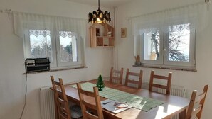 Un coin repas avec une table en bois, six chaises, un petit sapin de Noël et une suspension.