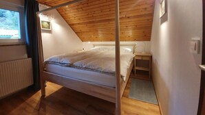 Une chambre à coucher avec un plafond en bois, un lit, une table de chevet et une fenêtre avec des rideaux.