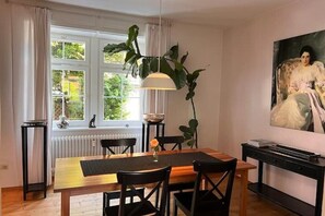 A dining room with a wooden table, black chairs, a hanging plant, and a painting on the wall. - Seeliebe | city location | seeglueck (Konstanz)