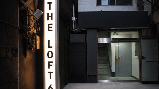Entrada de um edifício com uma placa que diz 'THE LOFT 6'.