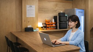 Uma pessoa usando um laptop em um balcão de madeira, com uma geladeira ao fundo.