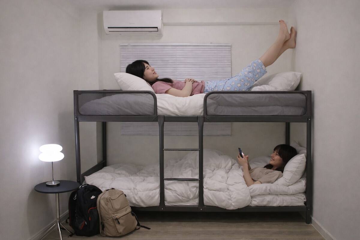 A bunk bed room with a standing desk and a lamp.
