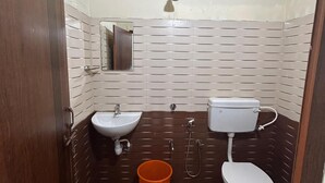 Un baño pequeño y funcional con puerta de madera, lavamanos, inodoro y ducha.
