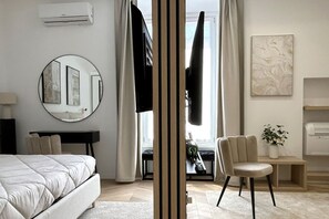A modern bedroom with a bed, a round mirror, a desk, and a chair. - Vatican Superior Suite (Roma)