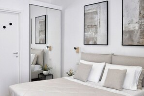 A bedroom with a bed, a nightstand, a mirror, and abstract art on the wall. - Vatican Superior Suite (Roma)