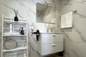 A modern bathroom with a white vanity, a large mirror, and a marble backsplash. - Vatican Superior Suite (Roma)