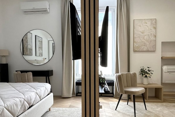 Ein modernes Schlafzimmer mit Bett, rundem Spiegel, Schreibtisch und Stuhl.