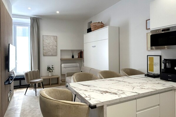 A modern kitchen with a marble countertop, a dining area with chairs, a TV, and a large window. - Vatican Superior Suite (Roma)