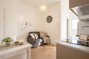Eine moderne Küche mit grauem Sofa, einem Topfpflanzen und einer Uhr an der Wand.